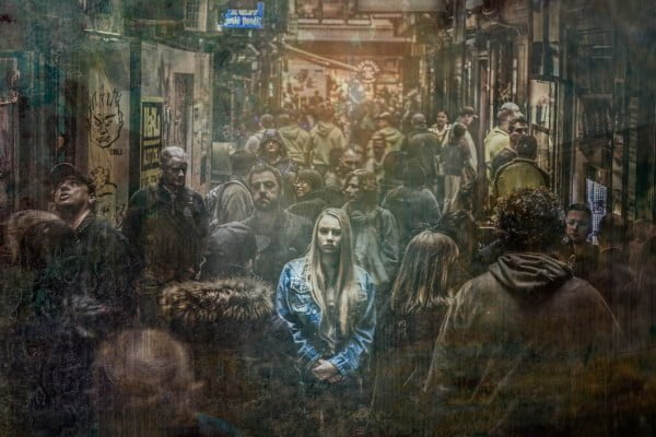 Mujer en la calle entre mucha gente. Está triste, deprimida