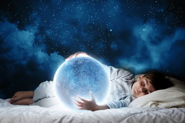 Insomnio vs sueño satisfactorio. El niño duerme en su cama abrazando la luna llena